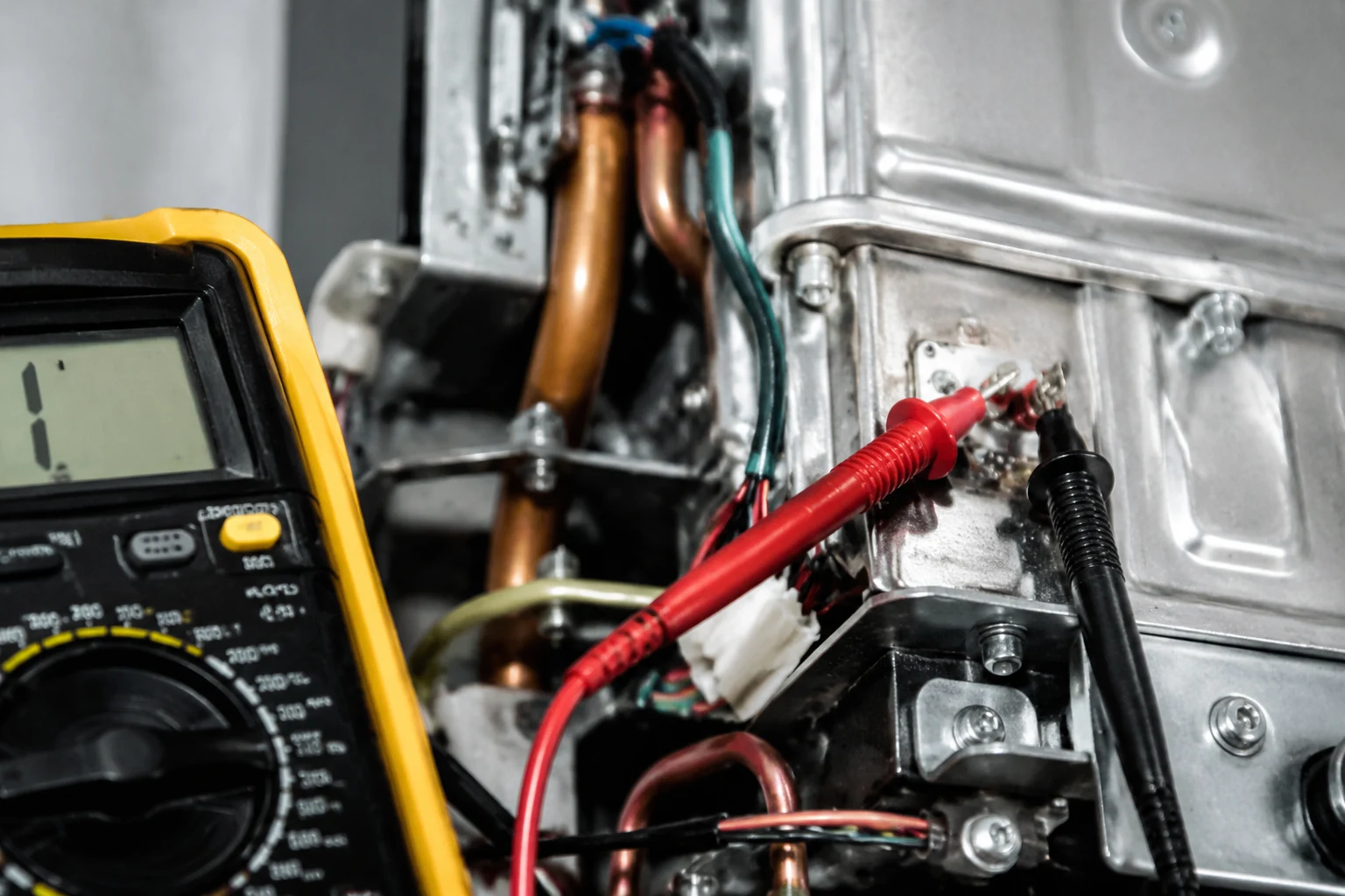 Technician connecting descale pump hoses to the isolation service valves on a wall-mounted Bosch tankless water heater