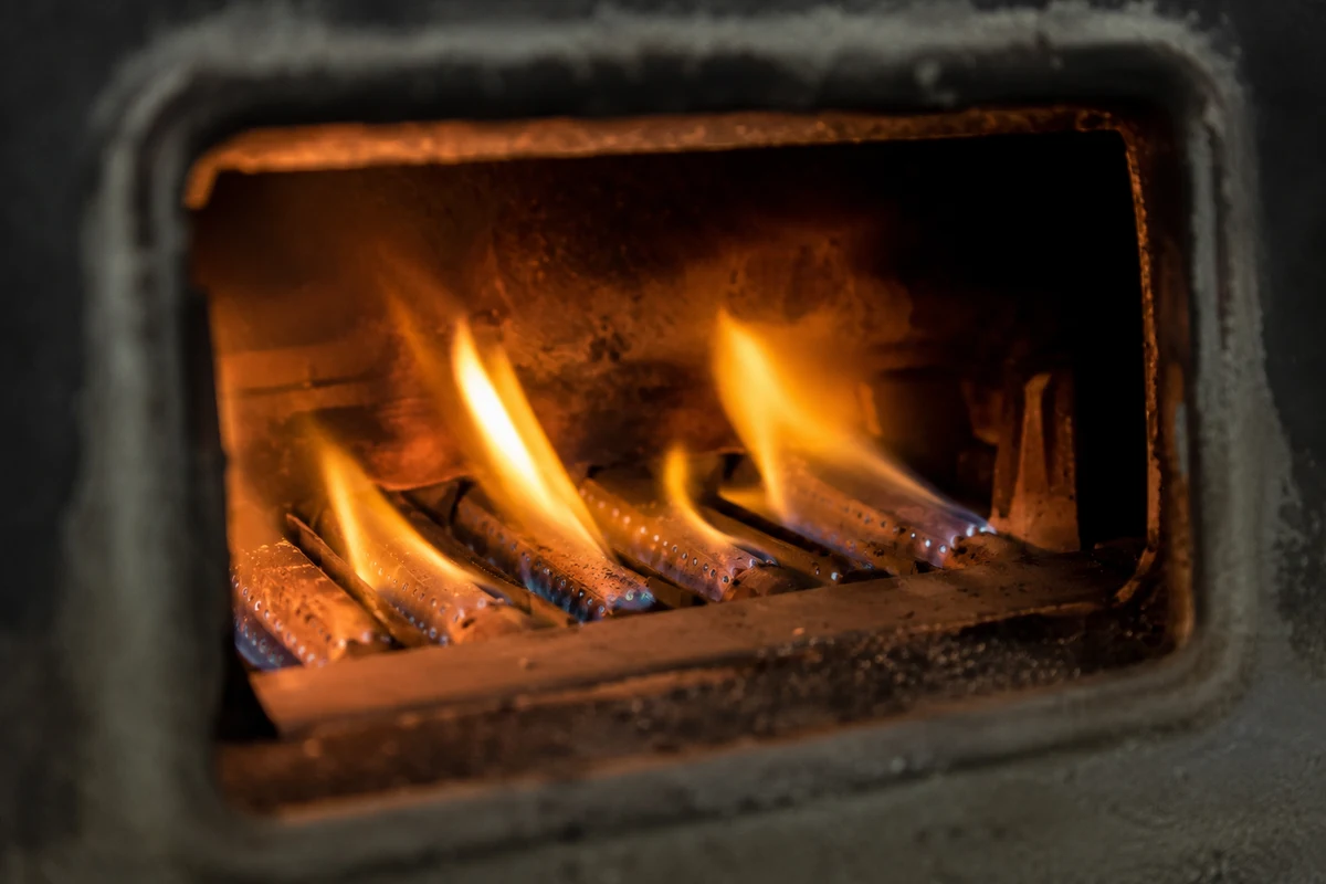View through the sight window of a gas water heater showing a yellow burner flame