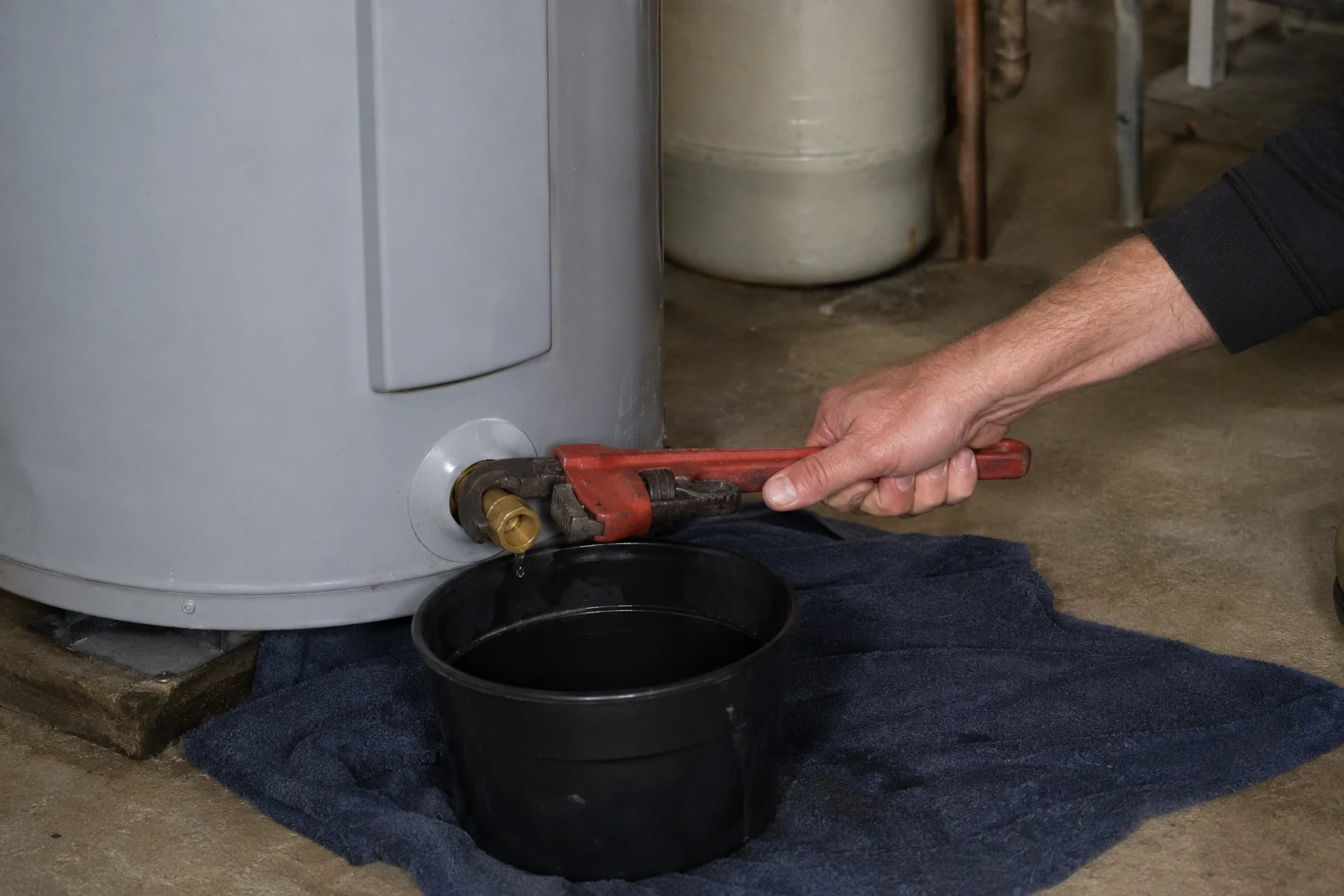 Brass full-port ball valve threaded into the drain port at the base of a water heater, replacing the old plastic valve
