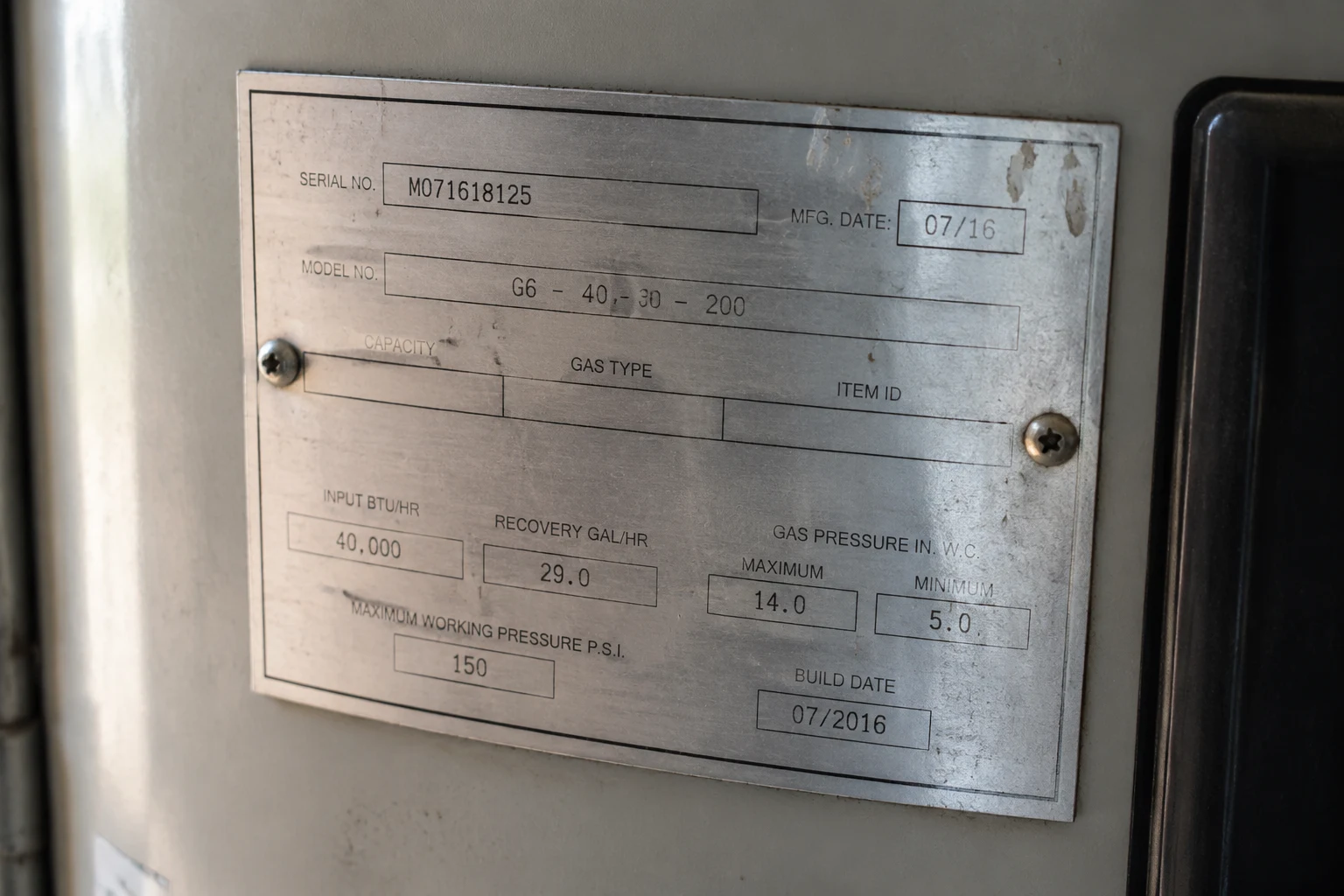 Close-up of a water heater rating plate sticker with the serial number line visible near the top of the tank