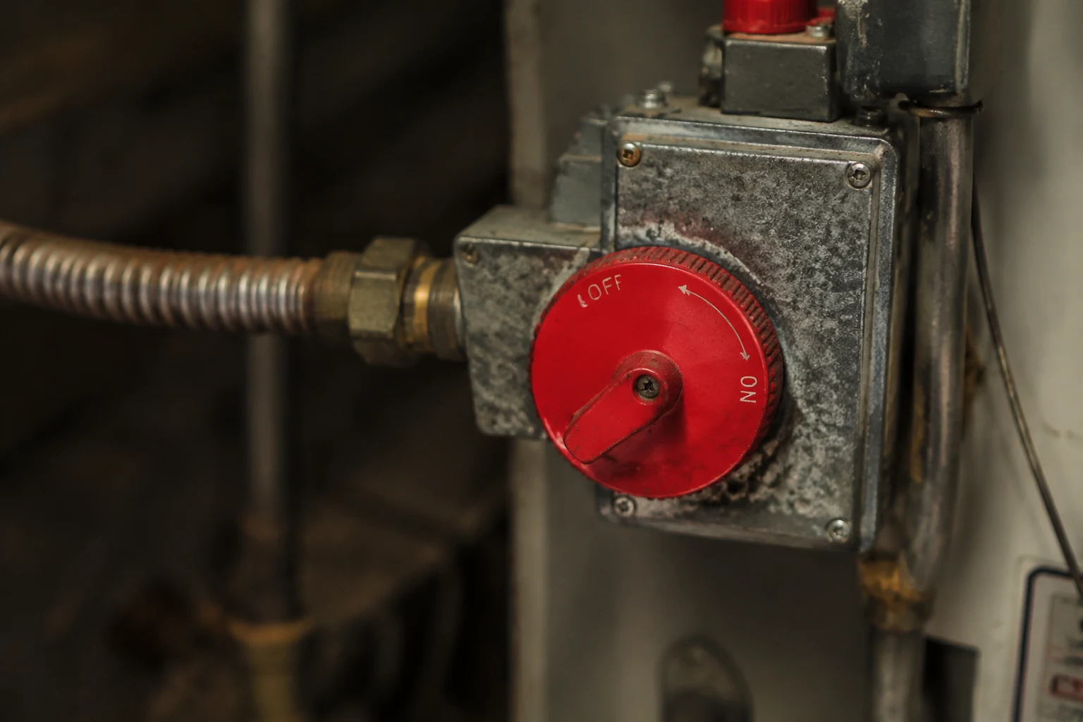 Close-up of a red gas control dial on the front of a water heater turned to the Off position