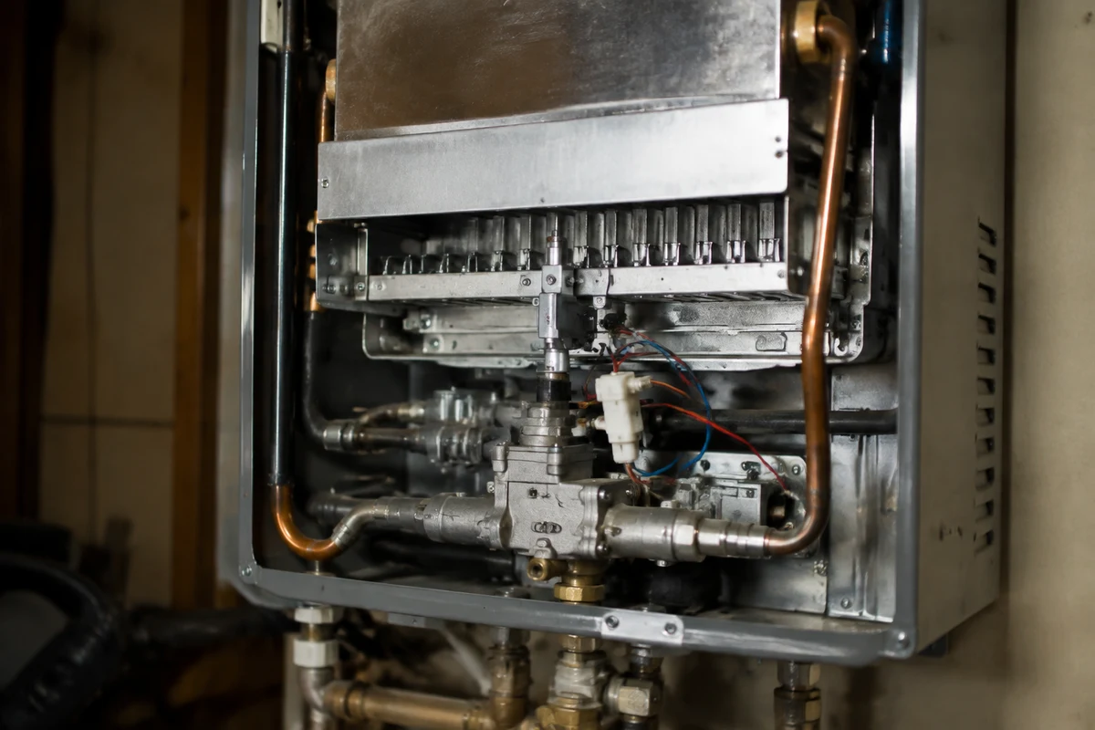 Inside a tankless water heater showing the burner assembly, igniter and gas manifold
