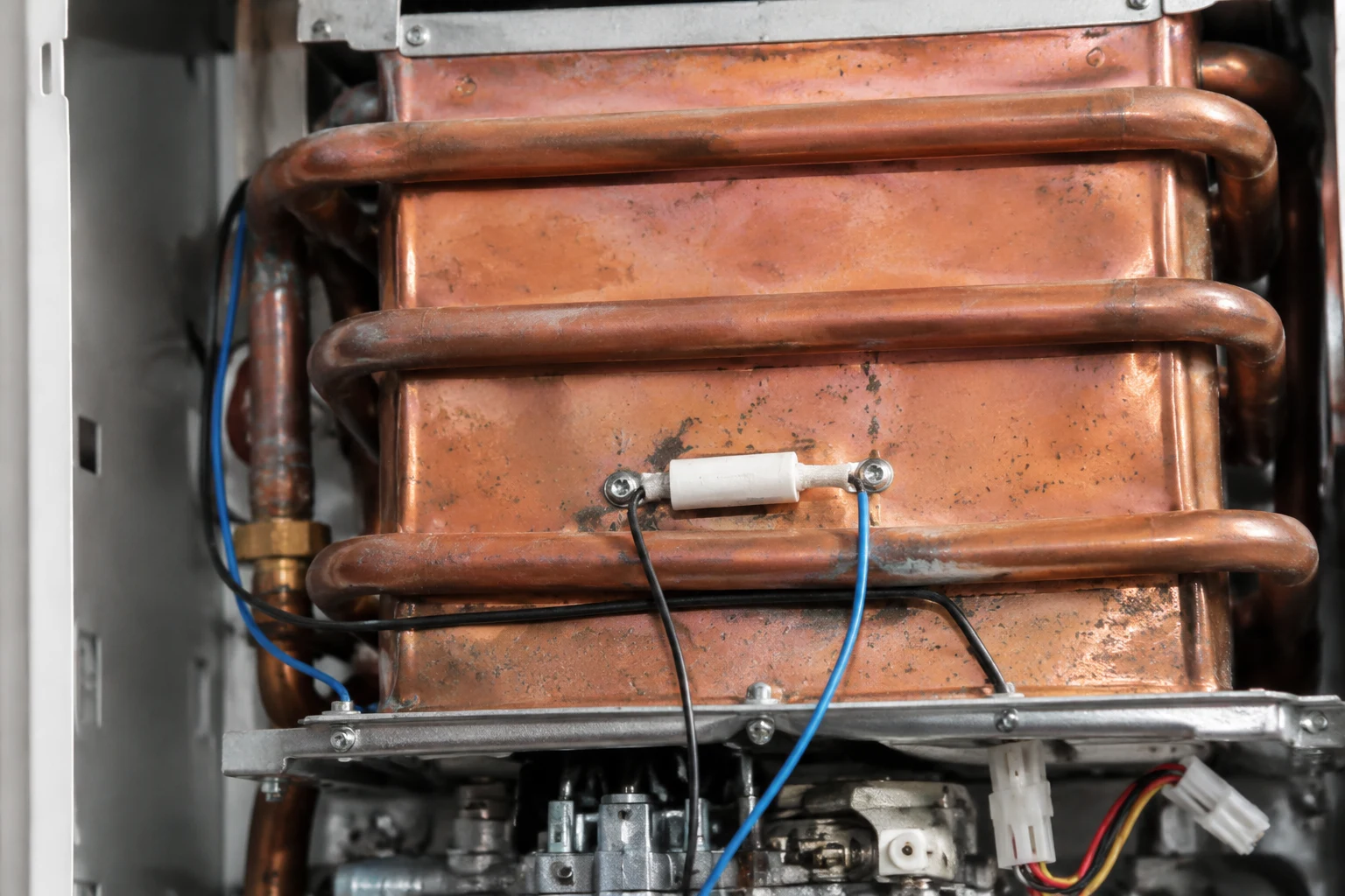 Technician removing the thermal fuse from the copper heat exchanger of a Noritz tankless water heater to clear error code 14
