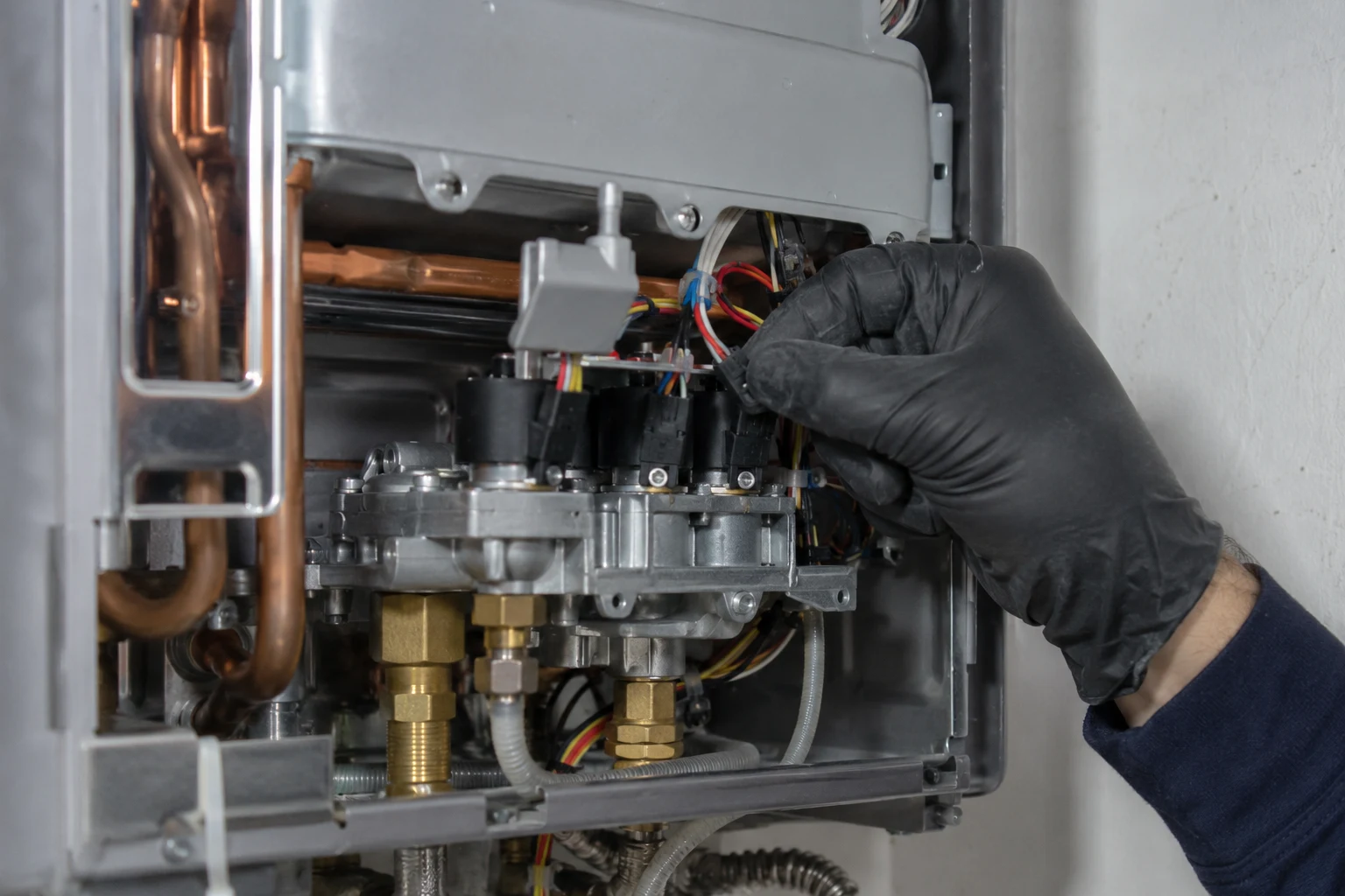 Technician measuring resistance on a Rinnai gas solenoid valve coil with a multimeter during code 71 diagnosis