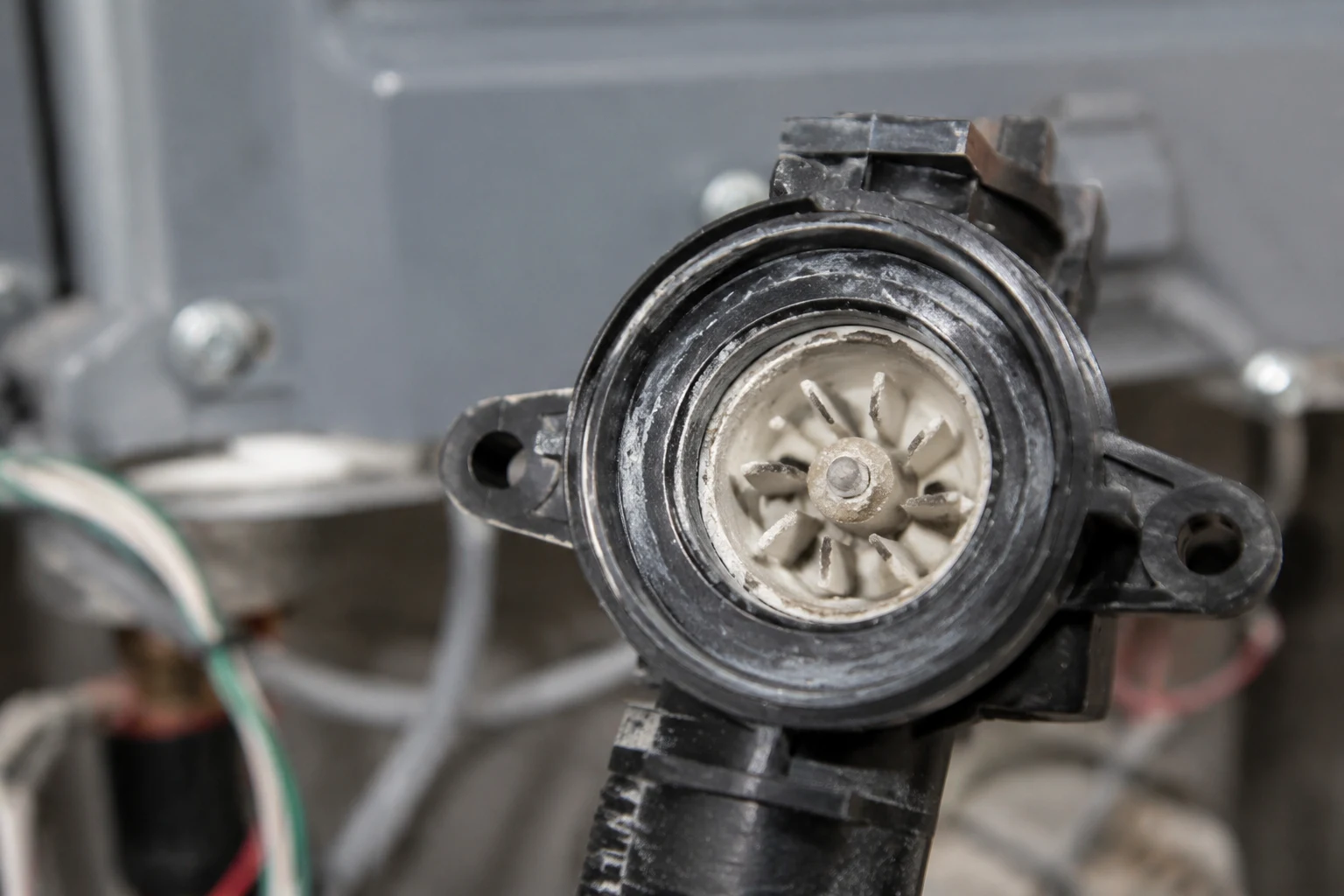 A tankless water heater flow sensor turbine removed from the cold inlet with scale being cleaned off the impeller