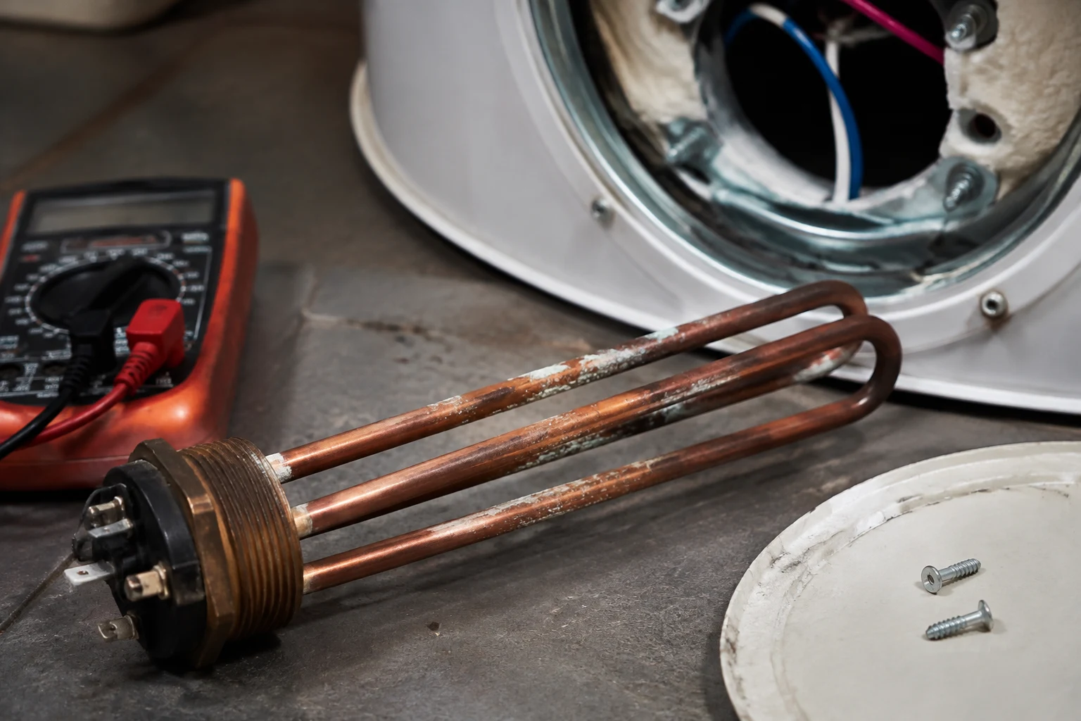 Water heater access panel removed exposing a screw-in heating element and its thermostat wiring